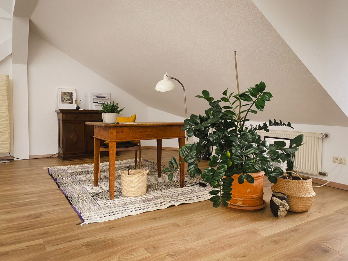 Schreibtisch mit Leuchte, Teppich und Pflanzen unter der Dachschräge
